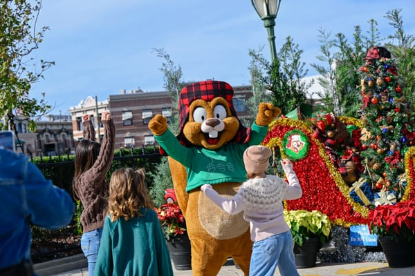 Earl the Squirrel dances with three girls in front of his sled at Universal Studios Florida.